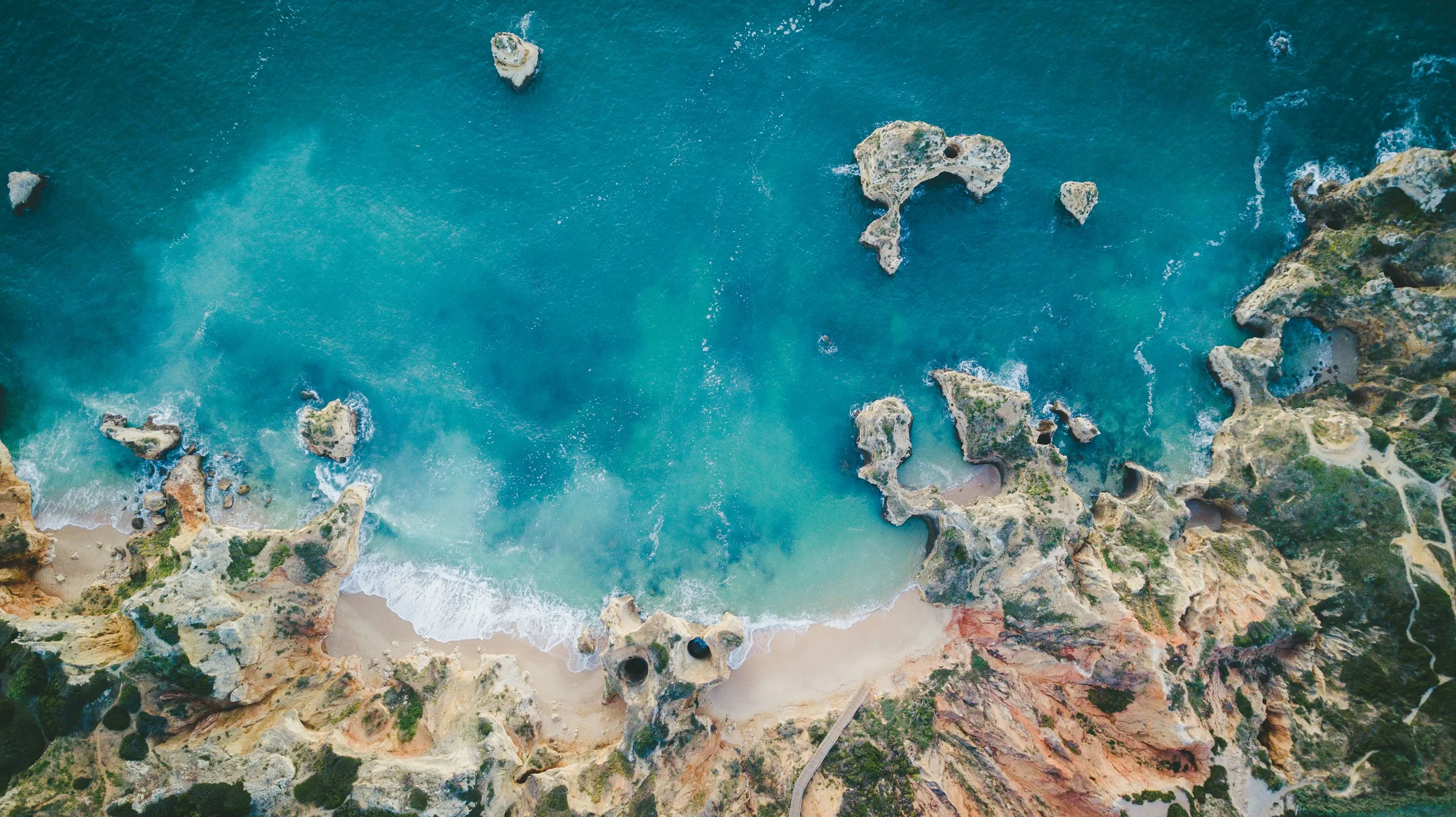 Falésias e enseadas de água turquesa no barlavento algarvio, vistas do ar